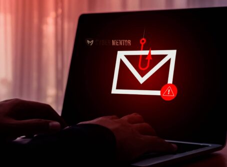 Imagen conceptual de un ataque Baiting mostrando un anzuelo sobre un icono de correo electrónico con una señal de advertencia en la pantalla de una laptop, con manos de una persona en el teclado.