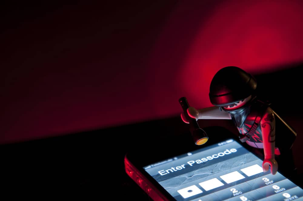 Imagen metafórica de un ladrón intentando acceder a un teléfono, representando la detección de stalkerware.