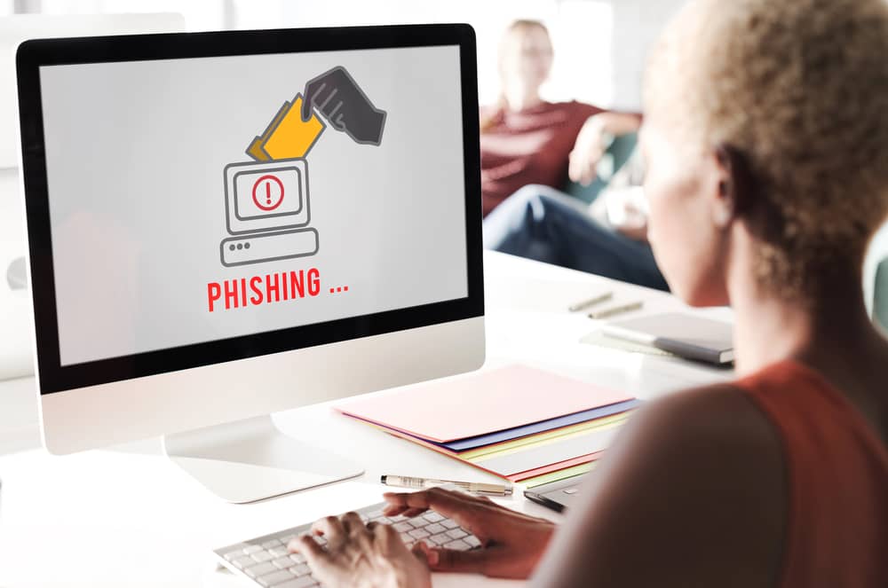 Imagen de una persona usando una computadora, con la palabra "phishing" en la pantalla, ilustrando un ataque de phishing.