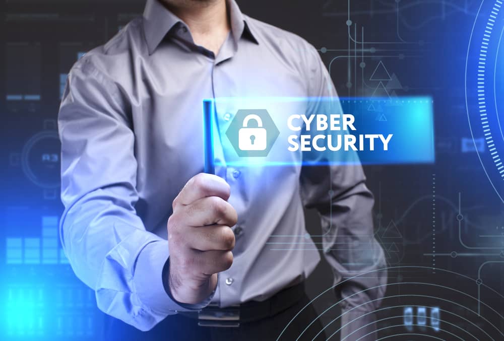 Una persona selecciona un elemento digital que dice "Ciberseguridad" con un icono de candado, representando la protección de datos y sistemas.