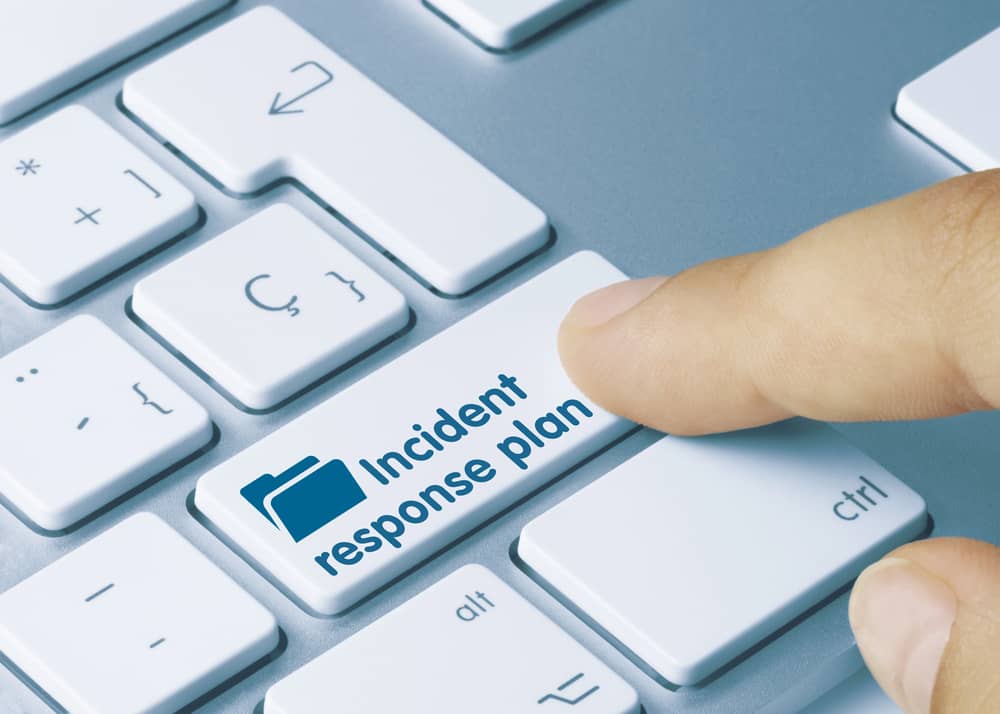 Un dedo presionando una tecla de un teclado que dice "Plan de respuesta a incidentes".