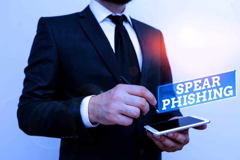 Imagen de un hombre de negocios con un smartphone ilustrando Qué es Spear Phishing y muestra la frase "Spear Phishing"