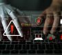 Mano robótica y humana teclean juntas en un teclado, con iconos de seguridad y alerta de phishing con IA. Descubre todo sobre el phishing impulsado por IA.
