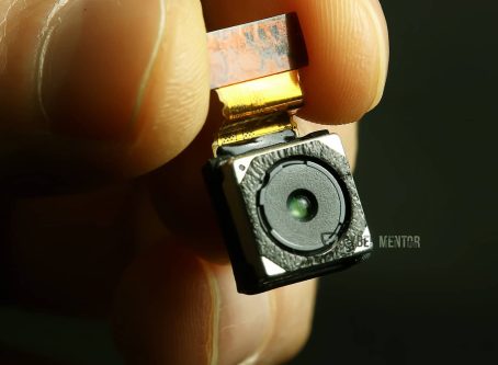 Diminuto módulo de una cámara oculta sostenido entre dos dedos.