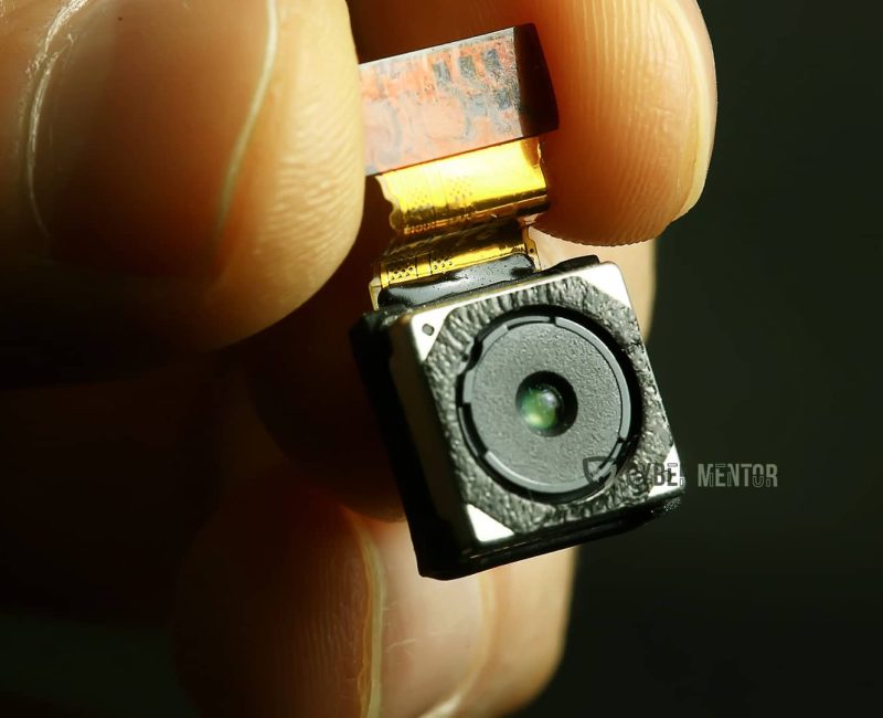 Diminuto módulo de una cámara oculta sostenido entre dos dedos.