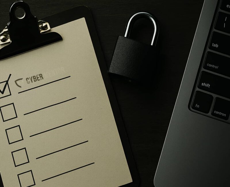 Checklist de seguridad informática con un candado y un portátil sobre un escritorio.
